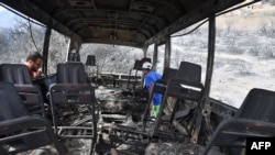 Des hommes algériens vérifient un bus carbonisé dans lequel au moins 12 personnes auraient été brûlées vives à la suite d'incendies qui ont fait rage dans la ville algérienne d'el-Kala le 18 août 2022.