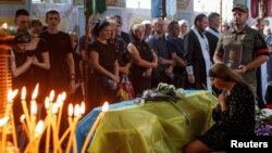 Viktoriia reacts next to a coffin with the body of her husband Vitalii Holubka, Ukrainian serviceman who was recently killed, during a funeral ceremony in the town of Chop, Zakarpattia region, Ukraine Aug. 17, 2022.