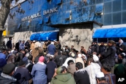 FILE - Afghan wait to enter a bank, in Kabul, Afghanistan, Feb. 13, 2022.