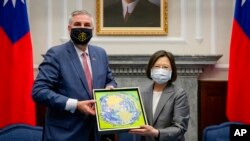 Taiwan's President Tsai Ing-wen, at right, exchanges gifts with U.S. Indiana Governor Eric Holcomb during a meeting at the Presidential office in Taipei, Taiwan, Aug 22, 2022, in this photo released by the Taiwan Presidential Office.