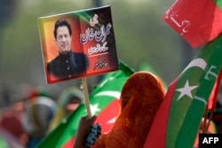 Seorang pendukung partai berkuasa Pakistan Tehreek-e-Insaf (PTI) memegang plakat bergambar mantan perdana menteri Pakistan Imran Khan pada 27 Maret 2022. (Foto: AFP/Aamir QURESHI)