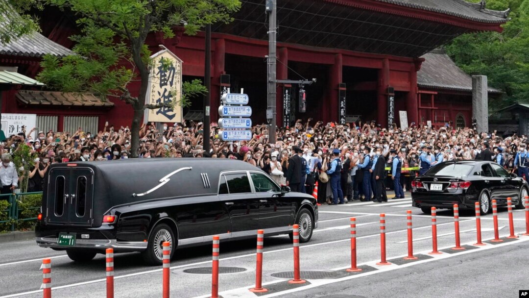 Kendaraan yang membawa jenazah mantan perdana menteri Jepang Shinzo Abe meninggalkan kuil Zojoji setelah pemakamannya di Tokyo pada 12 Juli 2022. (Foto: AP)