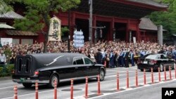 Kendaraan yang membawa jenazah mantan perdana menteri Jepang Shinzo Abe meninggalkan kuil Zojoji setelah pemakamannya di Tokyo pada 12 Juli 2022. (Foto: AP)