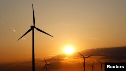 FILE - Power-generating windmill turbines are seen during the sunset at a wind park near Moenchhof, Austria, May 2, 2019.