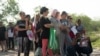 Migrantes que buscan asilo, en su mayoría de Venezuela y Cuba, esperan ser transportados por agentes de Aduanas y Protección Fronteriza de EEUU después de cruzar el río Bravo hacia EEUU desde México en Eagle Pass, Texas, el 13 de julio de 2022.