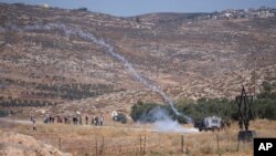 FILE - Israeli army troops use teargas canisters to disperse Palestinian protesters who burned tires and blocked the street that bypasses the West Bank village of Mughayer, north of Ramallah, July 29, 2022. 