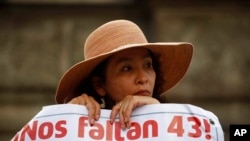 FILE - A woman carries a banner that reads in Spanish "We are missing 43," referring to the 43 missing students from a rural teachers college, during a march in Mexico City, Nov. 26, 2015.