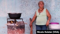 Cecilia Tarazona carga ella misma los pedazos de troncos secos que recoge en una montaña a una hora de camino de su casa. Foto Nicole Koslter, VOA. 