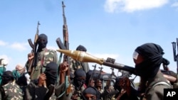 FILE - Armed al-Shabab fighters ride on pickup trucks as they prepare to travel into the city, just outside the capital of Mogadishu, Somalia, Dec. 8, 2008.