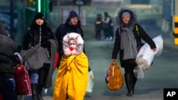 FILE - People fleeing the conflict in neighboring Ukraine cross the border in Przemysl, Poland, Feb. 27, 2022. 