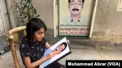 Arowa Islam, 11, sits with the photo of her father, opposition Bangladesh Nationalist Party leader Sajedul Islam Shuman, August 16, 2022. Shuman remains missing after RAB allegedly abducted him from Dhaka in 2013. (Photo by Mohammad Abrar for VOA)
