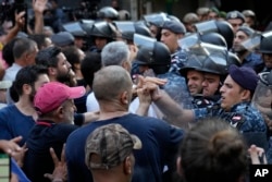 Petugas polisi anti huru hara Lebanon mendorong mundur pengunjuk rasa anti-bank yang datang untuk mendukung upaya penyanderaan yang dilakukan oleh seorang pria bersenjata di dalam sebuah bank, di Beirut, Lebanon, Kamis, 11 Agustus 2022. (AP/Hussein Malla)