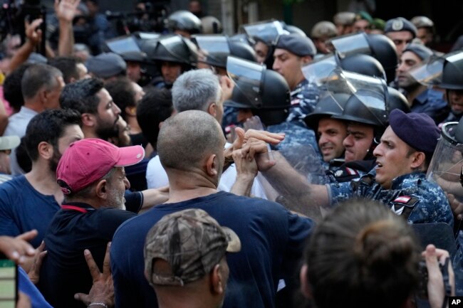 Petugas polisi anti huru hara Lebanon mendorong mundur pengunjuk rasa anti-bank yang datang untuk mendukung upaya penyanderaan yang dilakukan oleh seorang pria bersenjata di dalam sebuah bank, di Beirut, Lebanon, Kamis, 11 Agustus 2022. (AP/Hussein Malla)