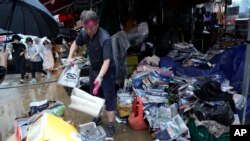 Seorang pemilik toko membersihkan sampah yang terbawa banjir di pasar tradisional Seoul, Korea Selatan, Selasa, 9 Agustus 2022. (AP/Ahn Young-joon)