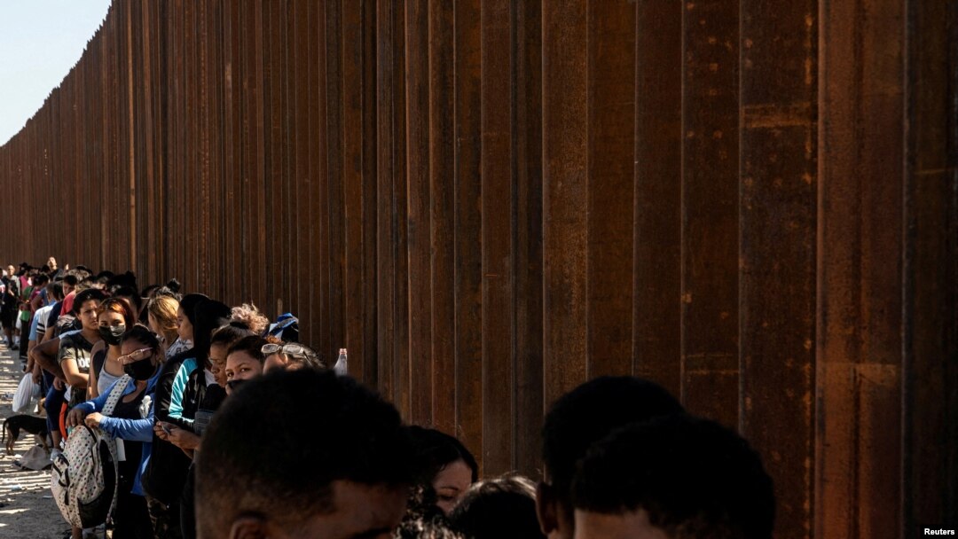 Migrantes que buscan asilo, en su mayoría de Venezuela y Cuba, esperan ser transportados por agentes de Aduanas y Protección Fronteriza de EE. UU. después de cruzar el río Bravo hacia EE. UU. desde México en Eagle Pass, Texas, EE. UU., 14 de julio de 2022.