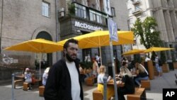 ARCHIVO - Gente come en las mesas en la acera de un McDonald's en el centro de Kiev, Ucrania, 9 de junio de 2020. McDonald's anunció el jueves 10 de agosto de 2022 que reabrirá locales en Ucrania en los próximos meses. (AP Foto/Efrem Lukatsky, File)