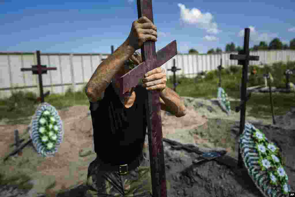 A funeral worker installs a cross with a number plate on the grave of an unidentified civilian killed by Russian troops during the Russian occupation in Bucha near Kyiv, Ukraine. Twenty-one unidentified bodies exhumed from a mass grave were buried in Bucha on Wednesday.