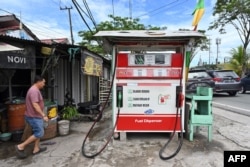 A man walks next to a mini gas station in Balikpapan, East Kalimantan on August 18, 2022. (Photo by ADEK BERRY / AFP)