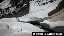 A group of people walk near a crevasse in a glacier in Sonmarg, Kashmir.