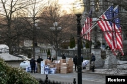 FILE - Workers move boxes out of the Eisenhower Executive Office Building on the White House grounds, before the departure of U.S. President Donald Trump, in Washington, Jan. 14, 2021.