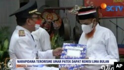 Terpidana militan Muslim Umar Patek (kanan), menerima surat pengurangan hukumannya dalam upacara di Penjara Porong, Sidoarjo, Jawa Tengah, Rabu, 17 Agustus 2022. (Tangkapan layar, Courtesy: SCTV/Vidio via AP)