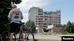 A biker pauses near a hotel recently hit by shelling in the course of Ukraine-Russia conflict in the Russian-controlled town of Svitlodarsk in the Donetsk region, Ukraine, August 8, 2022. A Russian offensive is continuing toward the cities of Bakhmut and Avdiyivka in the region.