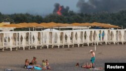 ARHIVA - Ljudi se odmaraju na plaži dok se dim i plamen uzdižu posle eksplozije u ruskoj vojnoj vazduhoplovnoj bazi u Novofedorivki na Krimu, 9. avgusta 2022.