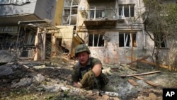A Ukrainian serviceman collects fragments in the crater to determine the type of ammunition after a Russian attack that damaged some buildings in Kharkiv, Aug. 30, 2022. 