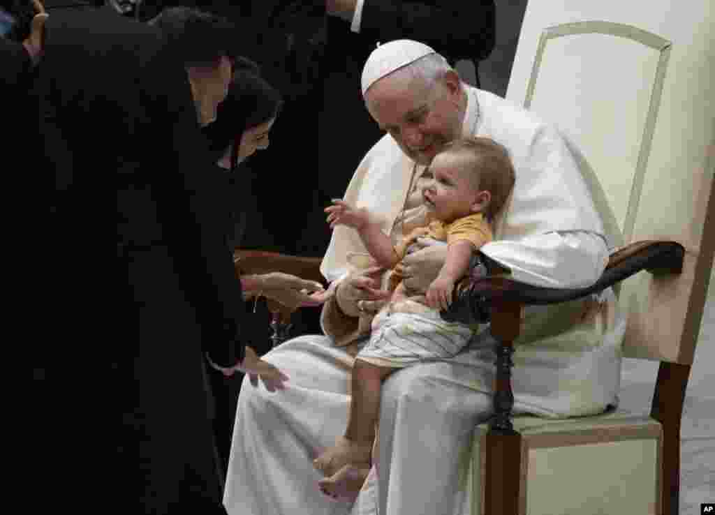 Pope Francis holds a child on his lap at the end of his weekly general audience in the Paul VI Hall at The Vatican.
