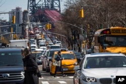 FILE - Pedestrians cross Delancey Street as congested traffic from Brooklyn enters Manhattan over the Williamsburg Bridge, March 28, 2019, in New York. (AP Photo/Mary Altaffer, File)