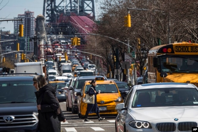 FILE - Pedestrians cross Delancey Street as congested traffic from Brooklyn enters Manhattan over the Williamsburg Bridge, March 28, 2019, in New York. (AP Photo/Mary Altaffer, File)