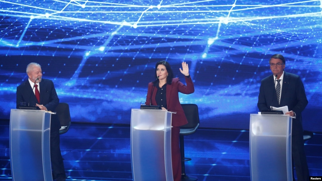 Simone Tebet, kandidat dalam pemilihan presiden Brazil, mengangkat tangannya di tengah sesi debat capres yang diikuti oleh Presiden Jair Bolsonaro (kanan), dan kandidat lainnya Luiz Inacio Lula da Silva, di Sao Paulo, Brazil, pada 28 Agustus 2022. (Foto: Reuters/Carla Carniel)