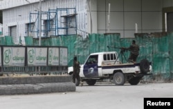 Somali police officers ride on their pick-up truck towards Hotel Hayat, the scene of an al Qaeda-linked al-Shabab group militant attack in Mogadishu, Somalia, Aug. 20, 2022.