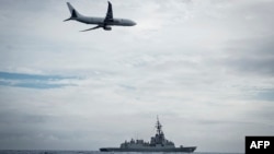 ແຟ້ມຮູບ-ເຮືອບິນ Poseidon P-8A ແຫ່ງກອງທັບອາກາດອອສເຕຣເລຍ ປະຕິບັດການບິນຕໍ່າ ຢູ່ເໜືອກໍາປັ່ນ HMAS Hobart ຂອງອອສເຕຣເລຍ ໃນລະຫວ່າງ ຊ່ວງໄລຍະການອອກໃບຮັບຮອງ ຂອງກອງທັບເຮືອ, ເມື່ອວັນທີ 24 ກຸມພາ 2022.