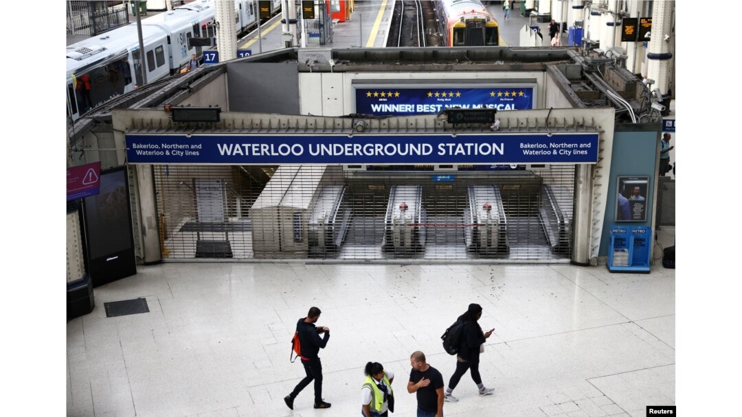Orang-orang berjalan melewati gerbang tertutup di pintu masuk stasiun Bawah Tanah Waterloo, London, Inggris, saat para pekerja di Kereta Bawah Tanah London melancarkan aksi mogok, 19 Agustus 2022. REUTERS/Henry Nicholls