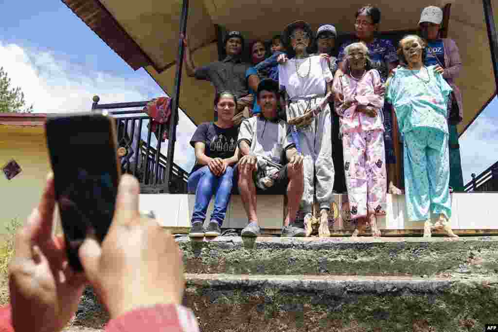 Family members perform the Manene traditional rite, cleaning the relatives' preserved remains, which is held every three years in August and is said to bless the harvest of rice fields, in Lembang, Indonesia.