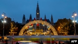 FILE - People stand outside of the traditional annual Christmas Market in front of Vienna's city hall in Vienna, Austria on Nov. 15, 2021.