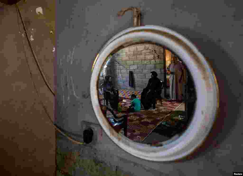 Family of Shadi Khail, who was killed in the recent Israel-Gaza fighting, are reflected in a mirror as they sit inside their home in Gaza City.