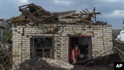 Olga Rudneva, residente de la localidad ucraniana de Druzhkivka, recupera un artículo para un anciano dueño de una casa dañada el jueves 18 de agosto de 2022 luego de un lanzamiento de cohetes rusos en la región de Donetsk, en el este de Ucrania. (AP Foto/David Goldman)