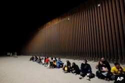 Migrantes esperando junto al final de un tramo de frontera el martes 23 de agosto de 2022 cerca de Yuma, Airzona. Foto AP.