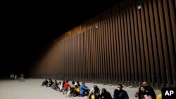 Migrantes esperando junto al final de un tramo de frontera el martes 23 de agosto de 2022 cerca de Yuma, Airzona.