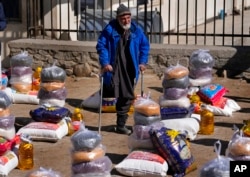FILE - An Afghan man stands between food supplies during a distribution of humanitarian aid for families in need, in Kabul, Afghanistan, Feb. 16, 2022.