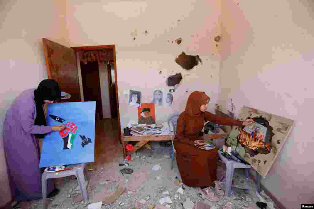 Palestinian artists draw paintings inside the damaged house of Gaza artist, Duniana Al-Amour, who had been killed during Israel-Gaza fighting earlier this month, in Khan Younis in the southern Gaza Strip.
