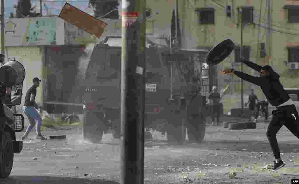 Palestinian youths throw objects at army vehicles during a military operation by the Israeli army to arrest wanted persons from the Balata camp near the West Bank city of Nablus.
