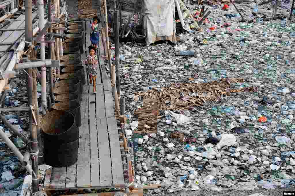 Local children Salsa, 7, and Riska, 8, run over a wooden bridge as they play at a slum area in the north coast of Jakarta, Indonesia.