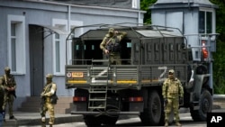 FILE - Russian soldiers guard an area as a group of foreign journalists visit in Kherson, Kherson region, south Ukraine, May 20, 2022.