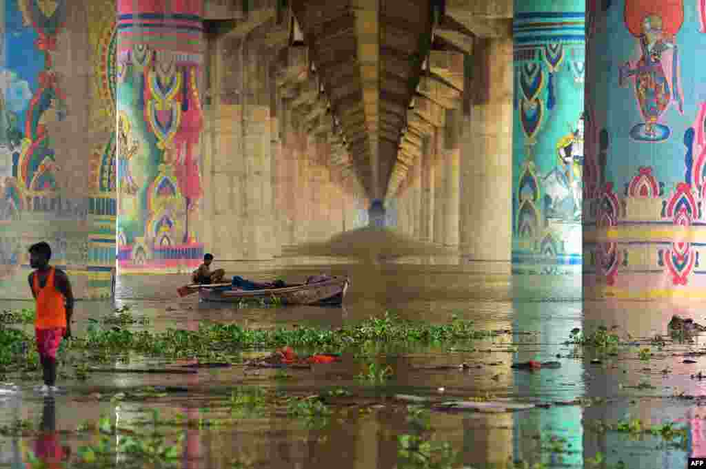 Men rest on a boat in the overflowed Ganges River under the Shastri Bridge in Allahabad, India, as water levels of the Ganges and Yamuna rivers rose following monsoon rainfalls.