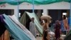 A displaced woman carries belongings in a light rain after fleeing her flood-hit homes in Sohbat Pur city, a district of Pakistan's southwestern Baluchistan province, Aug. 30, 2022.