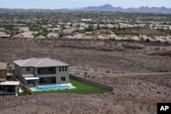 FILE - A home with a swimming pool abuts the desert on the edge of the Las Vegas valley, Wednesday, July 20, 2022, in Henderson, Nevada. (AP Photo/John Locher, File)