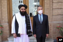 In this photo released by Xinhua News Agency, Chinese Foreign Minister Wang Yi poses for photos with Amir Khan Muttaqi, acting foreign minister of the Afghan Taliban's caretaker government, in Kabul, March 24, 2022. (Saifurahman Safi/Xinhua)